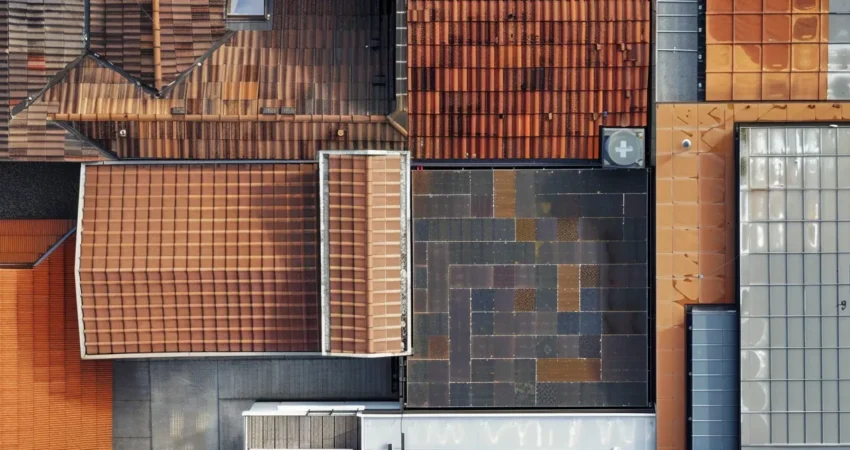 a dramatic aerial view of diverse commercial rooftops in various materials, showcasing the rich textures and colors under a bright, clear sky, highlighting the theme of roofing options.